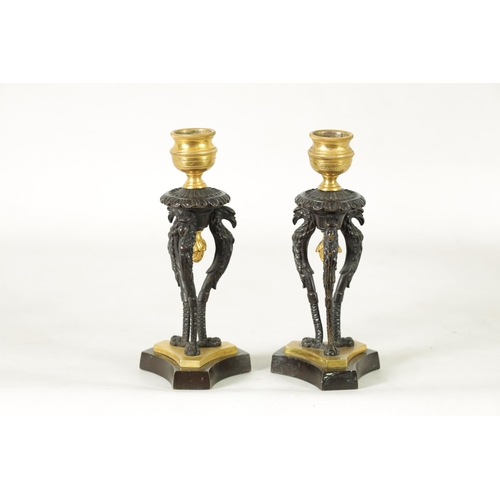 562 - A PAIR OF FRENCH EMPIRE BRONZE AND ORMOLU CANDLESTICKS with griffin mounts and triform pedestal base... 