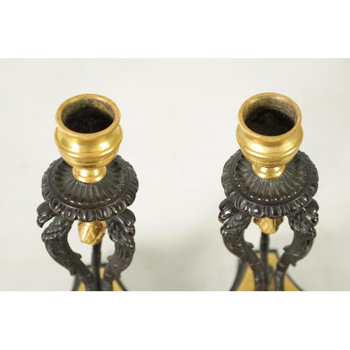 562 - A PAIR OF FRENCH EMPIRE BRONZE AND ORMOLU CANDLESTICKS with griffin mounts and triform pedestal base... 