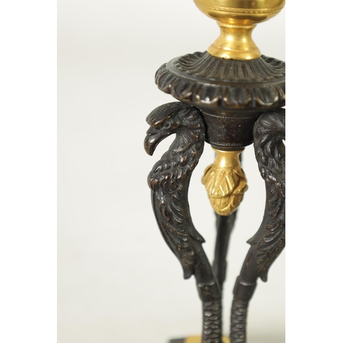 562 - A PAIR OF FRENCH EMPIRE BRONZE AND ORMOLU CANDLESTICKS with griffin mounts and triform pedestal base... 