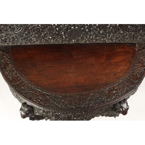 255 - A 19TH CENTURY ANGLO-INDIAN CARVED HARDWOOD DEMI LUNE SERVING TABLE with profusely carved and pierce... 