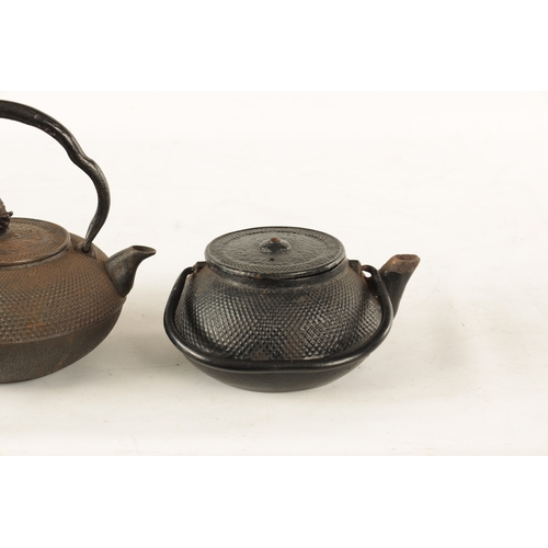 148 - TWO MEIJI PERIOD JAPANESE CAST IRON KETTLES both of squat bulbous form with textured decoration and ... 