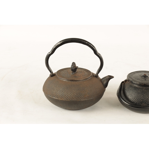 148 - TWO MEIJI PERIOD JAPANESE CAST IRON KETTLES both of squat bulbous form with textured decoration and ... 