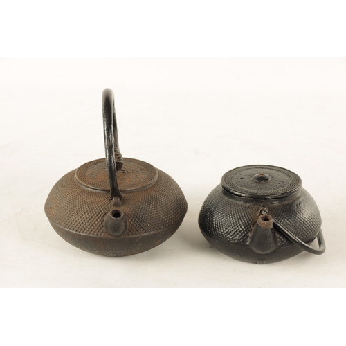 148 - TWO MEIJI PERIOD JAPANESE CAST IRON KETTLES both of squat bulbous form with textured decoration and ... 