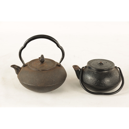 148 - TWO MEIJI PERIOD JAPANESE CAST IRON KETTLES both of squat bulbous form with textured decoration and ... 