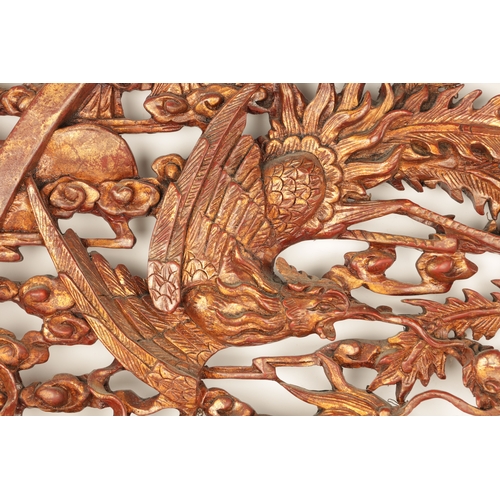 180 - A CHINESE CARVED LACQUERED HANGING PLAQUE having pierced centre depicting dragons amongst clouds (79... 