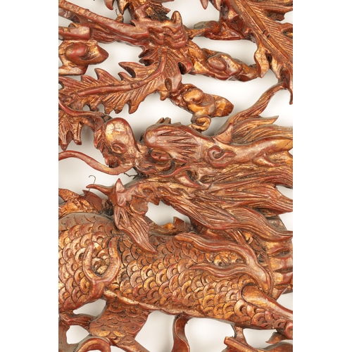 180 - A CHINESE CARVED LACQUERED HANGING PLAQUE having pierced centre depicting dragons amongst clouds (79... 