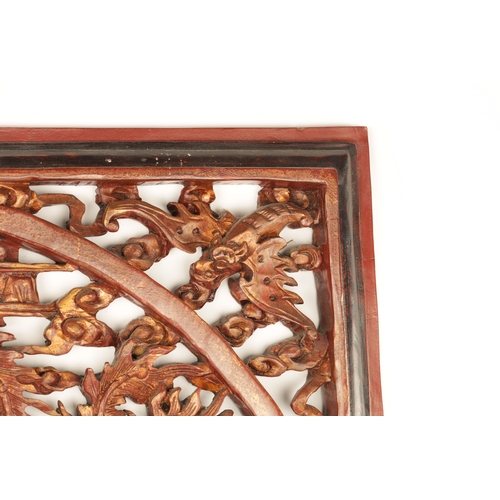 180 - A CHINESE CARVED LACQUERED HANGING PLAQUE having pierced centre depicting dragons amongst clouds (79... 