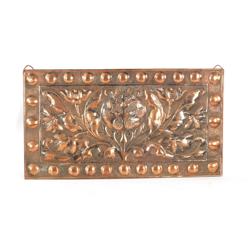 549 - AN ARTS AND CRAFTS PLANISHED COPPER AND EMBOSSED WALL PLAQUE with roundel design border and embossed... 