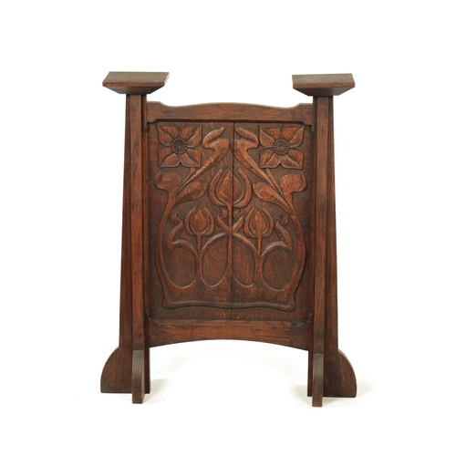 553 - A CARVED OAK ART NOUVEAU STYLE FIRE SCREEN with tulip carved panel raised on tapering side supports.... 