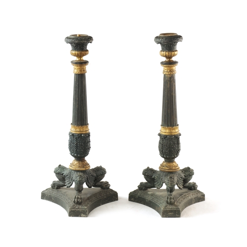 596 - A PAIR OF REGENCY-PATINATED METAL AND BRASS ORMOLU CANDLESTICKS with tapering reeded stems, leaf cas... 