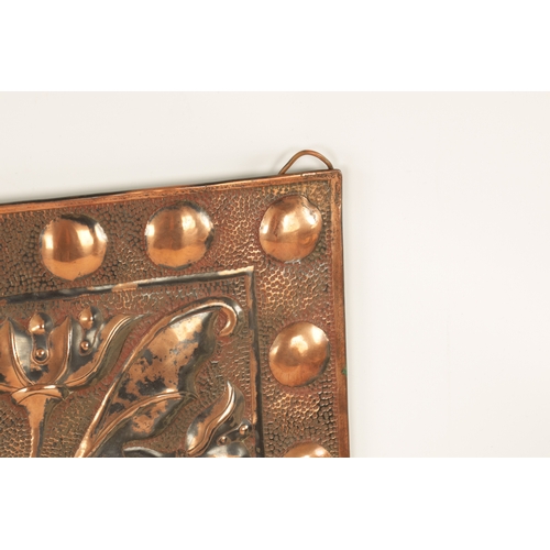 549 - AN ARTS AND CRAFTS PLANISHED COPPER AND EMBOSSED WALL PLAQUE with roundel design border and embossed... 