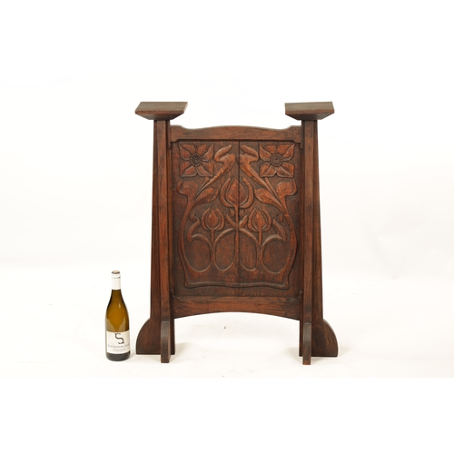 553 - A CARVED OAK ART NOUVEAU STYLE FIRE SCREEN with tulip carved panel raised on tapering side supports.... 