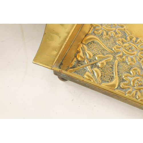 558 - AN STYLISH ARTS AND CRAFTS BRASS RECTANGULAR TRAY with shaped handles to the side and embossed flowe... 