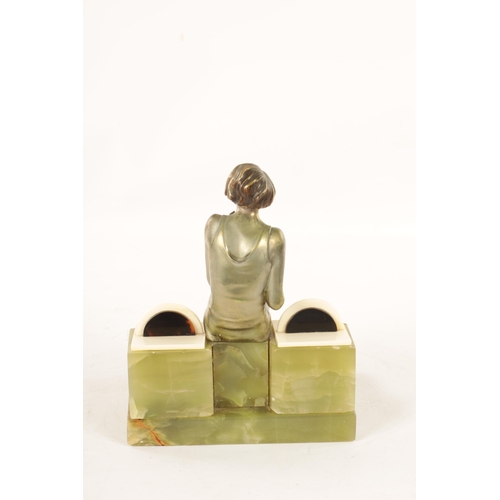 595 - ATT. JOSEF LORENZL. AN ART DECO SILVERED BRONZE FIGURAL INKSTAND modelled as a smoking girl seated o... 