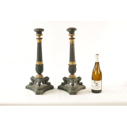 596 - A PAIR OF REGENCY-PATINATED METAL AND BRASS ORMOLU CANDLESTICKS with tapering reeded stems, leaf cas... 