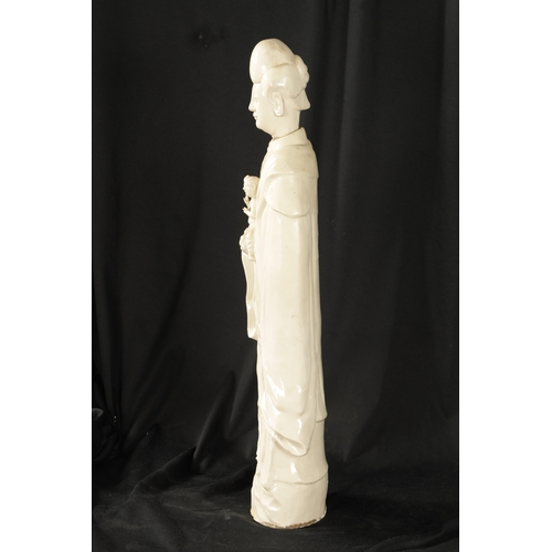 100 - A 19TH CENTURY CHINESE ‘BLANC DI CHINE’ STANDING FIGURE OF A GUAN modelled in flowing robes holding ... 