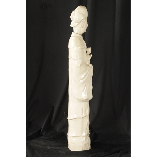 100 - A 19TH CENTURY CHINESE ‘BLANC DI CHINE’ STANDING FIGURE OF A GUAN modelled in flowing robes holding ... 