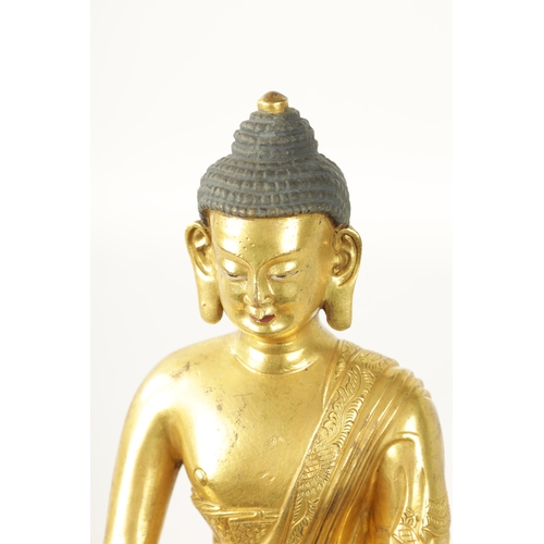 105 - AN EARLY CAST GILT BRONZE TIBETAN BUDDHA seated on a shaped leaf work base. (29cm high )