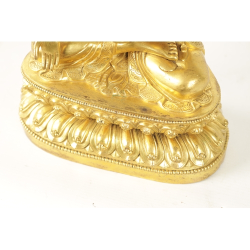 105 - AN EARLY CAST GILT BRONZE TIBETAN BUDDHA seated on a shaped leaf work base. (29cm high )