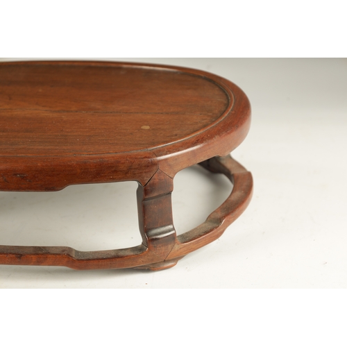 134 - A 19TH CENTURY CHINESE HARDWOOD OVAL SHAPED JARDINIERE STAND with shaped leg supports joined by a su... 