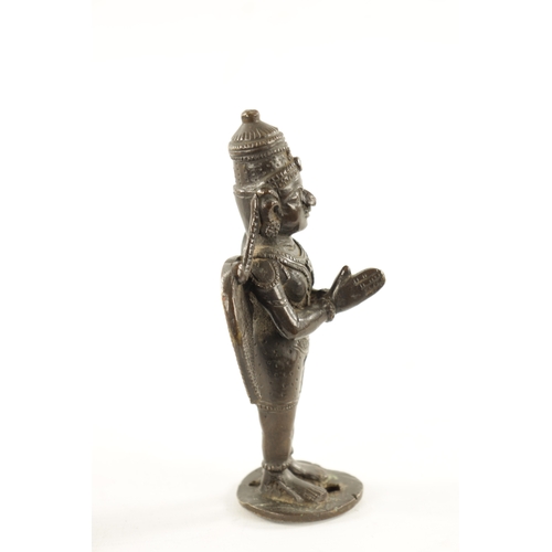 142 - AN EARLY INDIAN CAST BRONZE FIGURE OF A HINDU DEITY with hands closed and standing on a circular bas... 