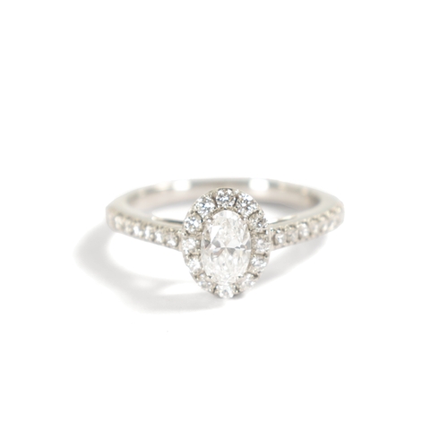 185 - A LADIES PLATINUM DIAMOND SOLITAIRE RING the an oval brilliant cut diamond surrounded by twelve smal... 