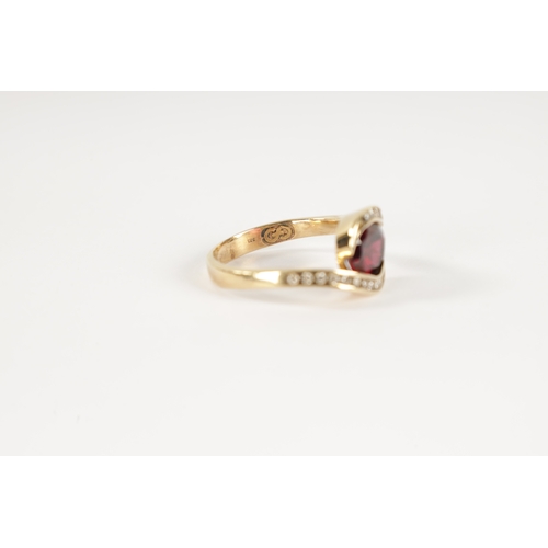 196 - A .375 HALLMARKED YELLOW GOLD AND GARNET SET DRESS RING the oval set stone in a swirled setting with... 