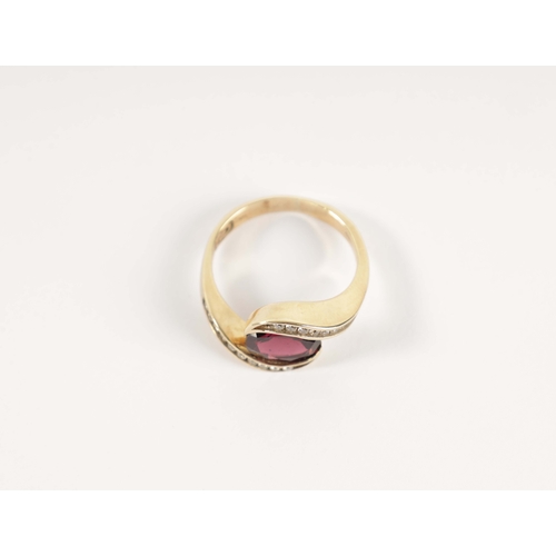 196 - A .375 HALLMARKED YELLOW GOLD AND GARNET SET DRESS RING the oval set stone in a swirled setting with... 