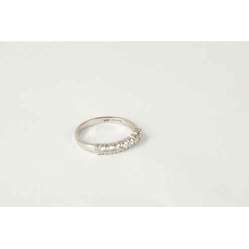 211 - A 7-STONE DIAMOND AND PLATINUM HALF-ETERNITY RING on a plain shank, size N.