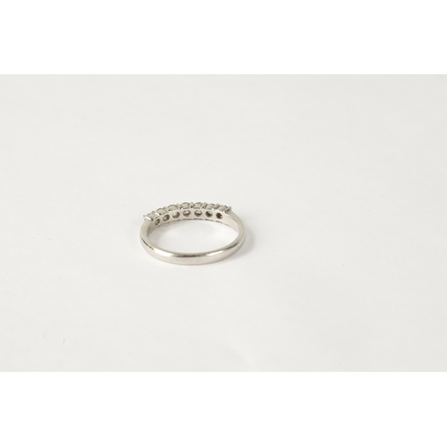 211 - A 7-STONE DIAMOND AND PLATINUM HALF-ETERNITY RING on a plain shank, size N.