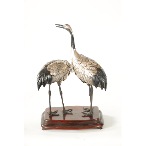 70 - A FINE JAPANESE MEIJI PERIOD SILVERED BRONZE OKIMONO OF TWO CRANES mounted on a moulded hardwood bas... 