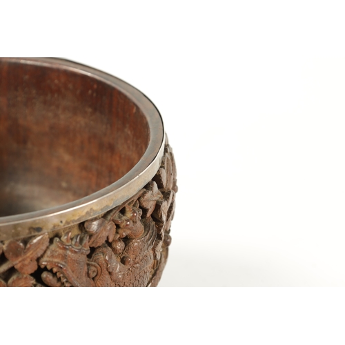 84 - A LATE 19TH CENTURY BURMESE CARVED HARDWOOD SILVER MOUNTED BOWL finely carved with dragons amongst l... 