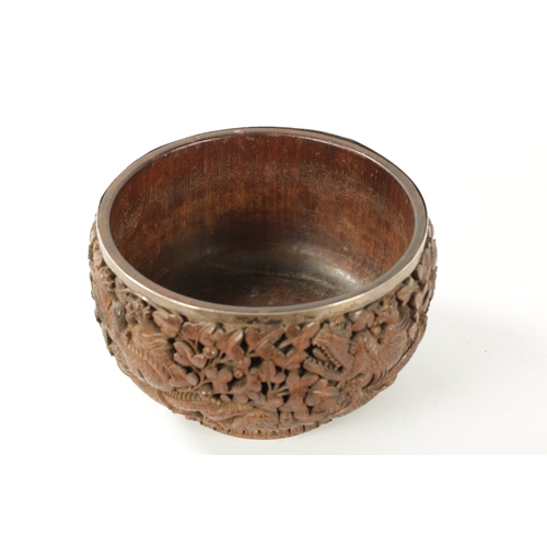 84 - A LATE 19TH CENTURY BURMESE CARVED HARDWOOD SILVER MOUNTED BOWL finely carved with dragons amongst l... 