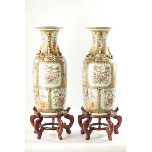 91 - A LARGE PAIR OF 19TH CENTURY CANTON FAMILLE ROSE VASES ON STANDS having panelled figural scenes and ... 