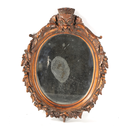 340 - A 19TH CENTURY CARVED WALNUT BLACK FOREST HANGING MIRROR with a monkey head pediment and leaf carved... 