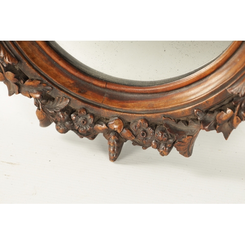 340 - A 19TH CENTURY CARVED WALNUT BLACK FOREST HANGING MIRROR with a monkey head pediment and leaf carved... 