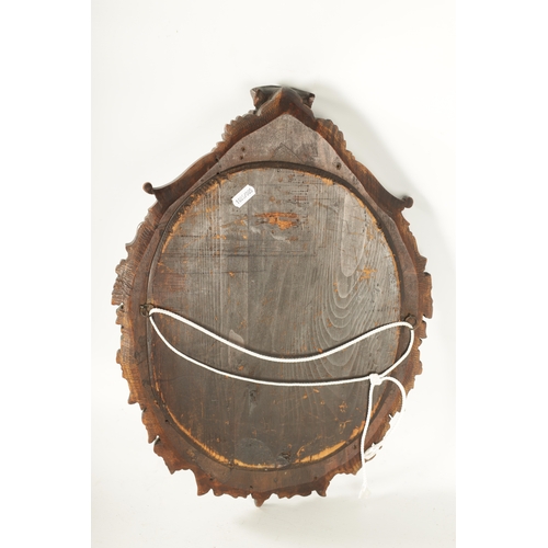 340 - A 19TH CENTURY CARVED WALNUT BLACK FOREST HANGING MIRROR with a monkey head pediment and leaf carved... 