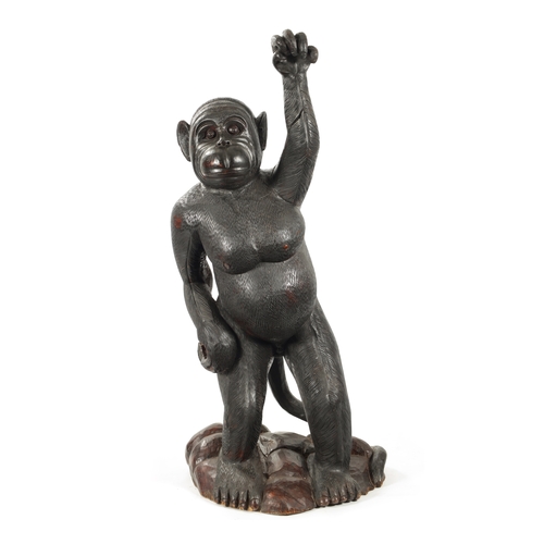 347 - A LIFE SIZE CARVED HARDWOOD SCULPTURE OF A STANDING MONKEY set on a naturalistic base. (145cm high)