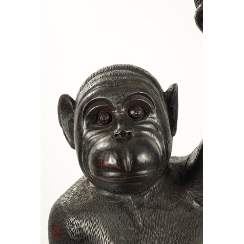 347 - A LIFE SIZE CARVED HARDWOOD SCULPTURE OF A STANDING MONKEY set on a naturalistic base. (145cm high)