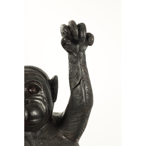 347 - A LIFE SIZE CARVED HARDWOOD SCULPTURE OF A STANDING MONKEY set on a naturalistic base. (145cm high)