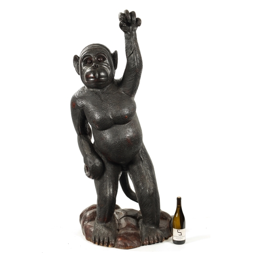 347 - A LIFE SIZE CARVED HARDWOOD SCULPTURE OF A STANDING MONKEY set on a naturalistic base. (145cm high)