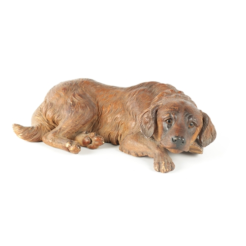 371 - AN 19TH CENTURY BLACK FOREST CARVED LINDEN WOOD SCULPTURE finely modelled as a recumbent dog with am... 