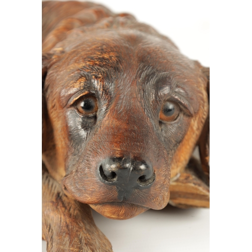 371 - AN 19TH CENTURY BLACK FOREST CARVED LINDEN WOOD SCULPTURE finely modelled as a recumbent dog with am... 