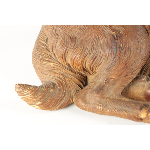 371 - AN 19TH CENTURY BLACK FOREST CARVED LINDEN WOOD SCULPTURE finely modelled as a recumbent dog with am... 