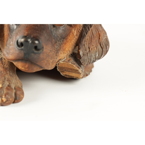 371 - AN 19TH CENTURY BLACK FOREST CARVED LINDEN WOOD SCULPTURE finely modelled as a recumbent dog with am... 