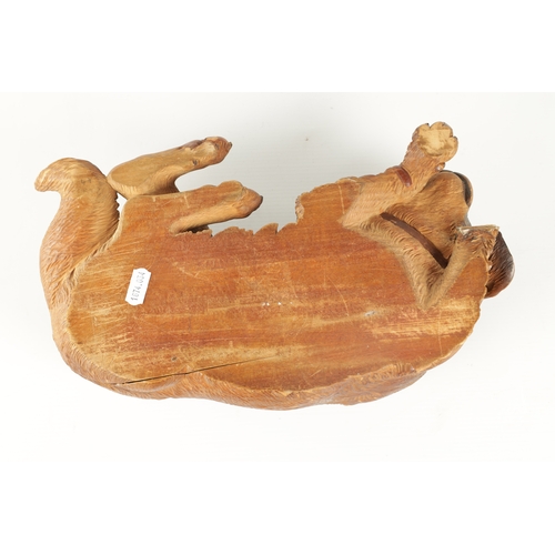 371 - AN 19TH CENTURY BLACK FOREST CARVED LINDEN WOOD SCULPTURE finely modelled as a recumbent dog with am... 