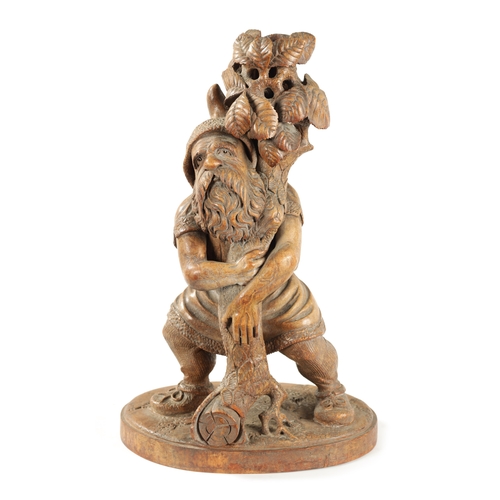 382 - A 19TH CENTURY BLACK FOREST CARVED LINDEN WOOD FIGURE depicting a standing gnome holding a leafing b... 