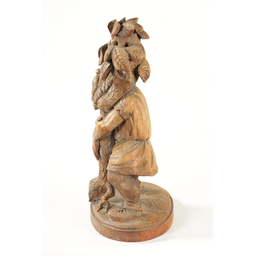 382 - A 19TH CENTURY BLACK FOREST CARVED LINDEN WOOD FIGURE depicting a standing gnome holding a leafing b... 