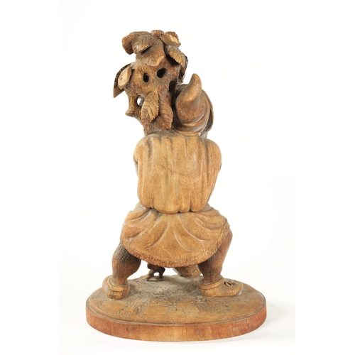 382 - A 19TH CENTURY BLACK FOREST CARVED LINDEN WOOD FIGURE depicting a standing gnome holding a leafing b... 