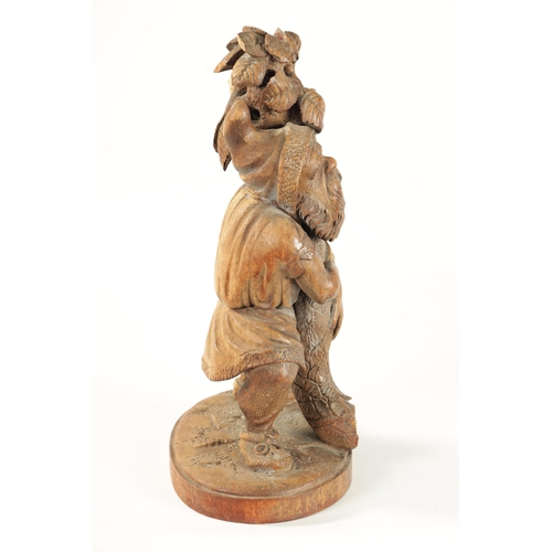 382 - A 19TH CENTURY BLACK FOREST CARVED LINDEN WOOD FIGURE depicting a standing gnome holding a leafing b... 